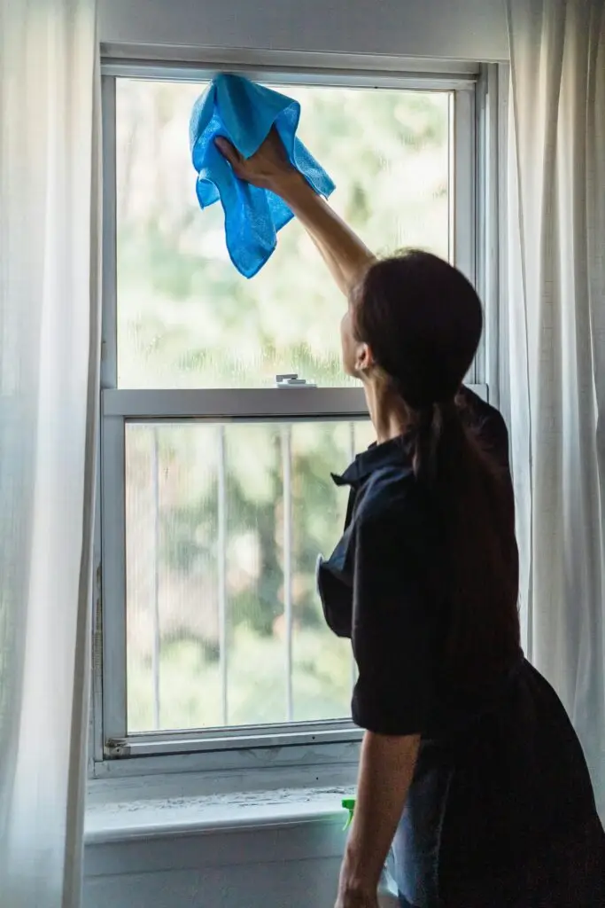 Person putsar fönster under flyttstädning i Kristianstad för skinande resultat